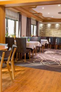 a dining room with tables and chairs and windows at Hotel Lang in Breidenbach