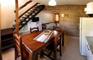 a kitchen and dining room with a wooden table and stairs at CABAÑAS AGUARI in Santa Rosa de Calamuchita