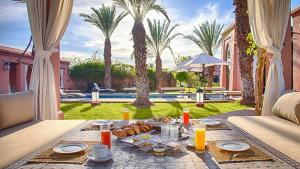 a table with food and drinks on a patio with palm trees at Palmeraie Dar Atlas - Luxury Houses in Marrakesh