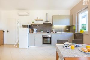 a kitchen with white appliances and a table with a plate of food at Apartment Andrea in Sveta Marina