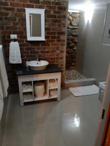 a bathroom with a sink and a brick wall at Arend Cottage in Nelspruit