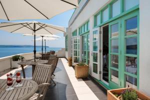 a patio with tables and umbrellas on a building at Burgh Island Hotel in Bigbury on Sea