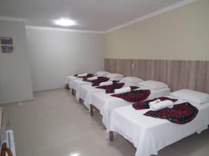 una fila di letti bianchi in una stanza di Pousada Treze de Março a Cachoeira