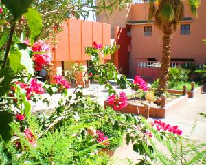 un jardin avec des fleurs roses devant un bâtiment dans l'établissement Hotel La Gazelle, à Ouarzazate