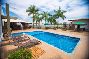 a swimming pool with chairs and a fountain at Ville Hotel Gramadão in Votuporanga