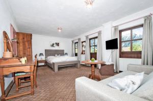ein Wohnzimmer mit einem Sofa, einem Bett und einem Schreibtisch in der Unterkunft Hotel Unterbrunn Apartments & Gästehaus in Neukirchen am Großvenediger