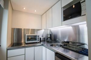a kitchen with white cabinets and a microwave and a sink at Live & Enjoy Buenos Aires in Central Recoleta powered by Argenhost -A12J- in Buenos Aires