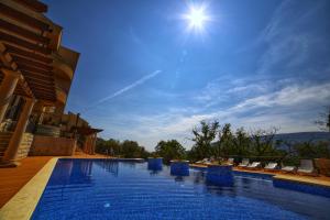 a swimming pool with chairs and the sun in the sky at Complex Adria Montenegro in Herceg-Novi