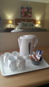 eine Kaffeemaschine und Tassen auf einem Tablett auf dem Tisch in der Unterkunft Kleines Nest Bed and Breakfast in Walvis Bay