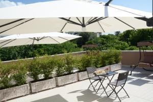 a patio with two white umbrellas and a table and chairs at Sylva Mala Home in Trecase