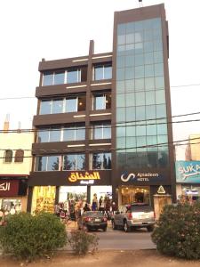 伊尔比德Ajnadeen Hotel的一座大楼，前面停满了汽车