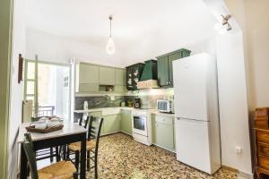 eine Küche mit grünen Schränken, einem Tisch und einem Kühlschrank in der Unterkunft Sea View Penthouse with Roof Garden in Chania
