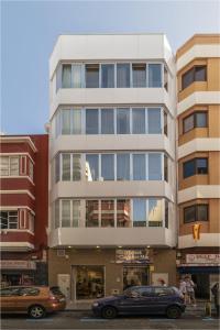 Un edificio alto con coches aparcados delante. en Hotel Ciudad del Mar, en Las Palmas de Gran Canaria