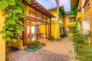 a courtyard of a house with yellow walls and plants at Surf Inn Bahia in Itacaré