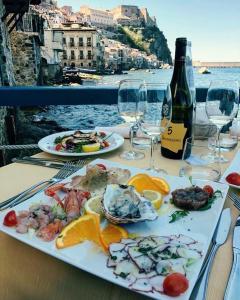 a table with a plate of food and a bottle of wine at Casa delle Galee in Scilla