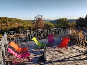 4 sillas coloridas sentadas en una terraza de madera en Le Domaine des Ramonets, en Cahors