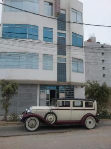 um carro velho estacionado em frente a um edifício em Hospedaje Harjeny em Trujillo