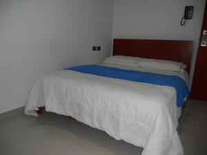 een slaapkamer met een groot wit bed met blauwe lakens bij Hotel Manzanares Baranoa in Baranoa