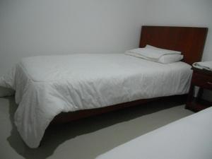 um quarto com uma cama branca e uma cabeceira em madeira em Hotel Manzanares Baranoa em Baranoa