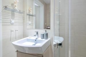 Un baño blanco con lavabo y ducha. en Kopernika8 Miro Apartment with Balcony and AC, en Cracovia