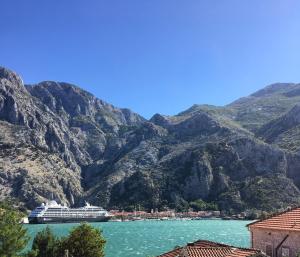 a cruise ship in the water next to mountains at Apartments Darija in Kotor