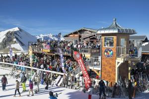 a crowd of people standing around a ski lodge at Le Montana in Les Deux Alpes