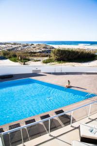 a person sitting in a swimming pool next to the beach at The Beachfront - Praia D'El Rey Golf & Beach Resort in Casal da Lagoa Seca