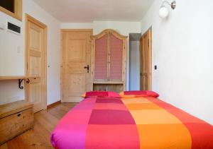 een groot kleurrijk bed in een kamer met houten vloeren bij premesan in Bormio