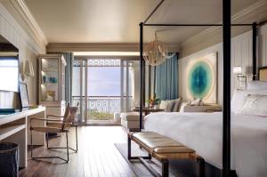 a hotel room with a bed and a desk and a balcony at Rosewood Baha Mar in Nassau