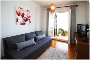 een woonkamer met een blauwe bank en een televisie bij Apartment Slavko in Primošten