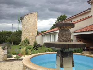 a large stone building with a pool of water in front of it at LOGIS Hôtel Le Moulin Des Gardelles in Riom