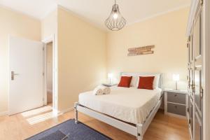 a white bedroom with a bed with orange pillows at Feel at home - Free private parking in Braga