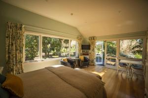 a bedroom with a large bed and large windows at Waipara River Estate in Waipara