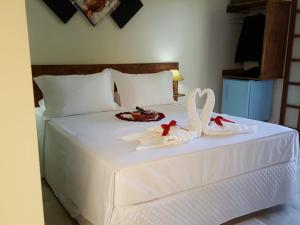Una cama blanca con dos toallas de cisne. en Pousada Mirante Do Lago en Lindóia