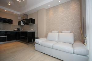 a living room with a white couch and a kitchen at Apartamenty Triston Park in Warsaw