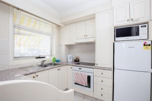 a kitchen with white cabinets and a white refrigerator at Broadbeach in Gold Coast
