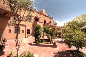 a courtyard of an old building with trees and bushes at Jardin de la source in Aït Yous