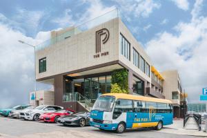 un autobús estacionado frente a un edificio con coches aparcados en The Pier Hotel, en Hong Kong