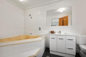 a bathroom with a sink, toilet and bathtub at Quest Trinity House in Hobart