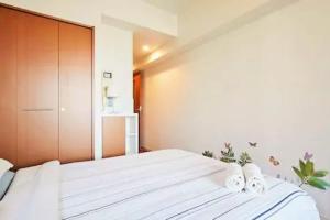 a bedroom with a large white bed with a wooden headboard at Certified Sanitise MIKO's Apartment Iconic Shinjuku Tokyo, 10th fl, skyscraper city view in Tokyo