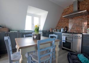 a kitchen with a wooden table and blue chairs at The Loft Midhurst in Midhurst