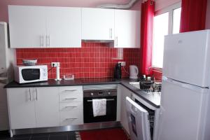 a kitchen with white cabinets and a red tiled wall at Vila Centro in Vila Franca do Campo