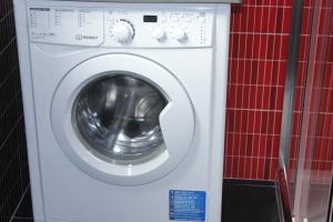 eine weiße Waschmaschine in einem rot gefliesten Zimmer in der Unterkunft Vila Centro in Vila Franca do Campo + 7 Fotos