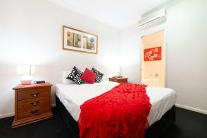 a bedroom with a bed with a red blanket at Cairns City Apartments in Cairns