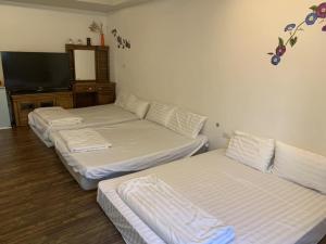 3 Betten in einem Zimmer mit einem TV in der Unterkunft 福緣白龍宮海景 in Xiaoliuqiu