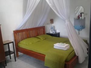 a bedroom with a green bed with a mosquito net at Jojo's Homestay and Warung in Munduk