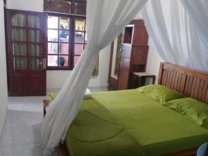 a bedroom with a green bed with a canopy at Jojo's Warung & Homestay in Munduk