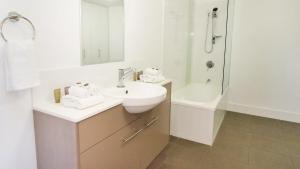 a white bathroom with a sink and a shower at Oaks Townsville Gateway Suites in Townsville