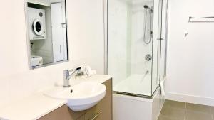 a white bathroom with a sink and a shower at Oaks Townsville Gateway Suites in Townsville