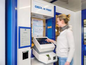 a woman is standing next to an atm machine at Ibis Budget Versailles Coignieres in Coignières